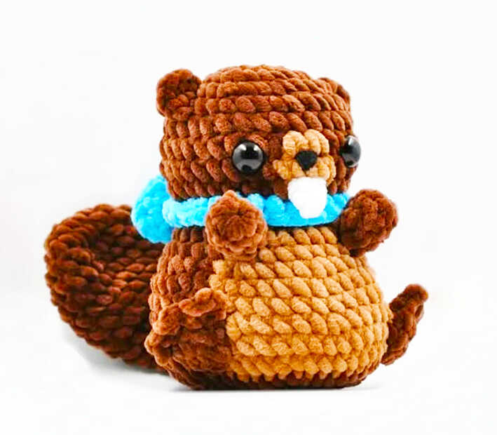 Cute plush amigurumi beaver with a blue scarf and chunky textured yarn