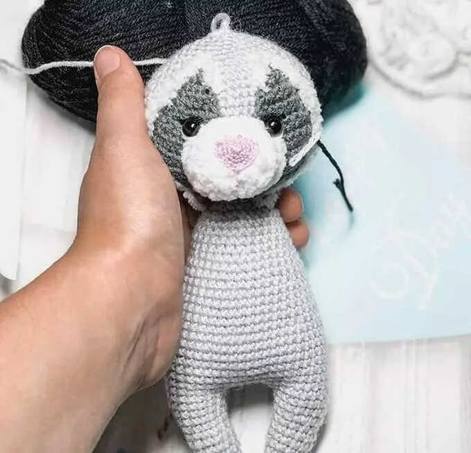 Raccoon amigurumi head attached to body during crochet assembly process