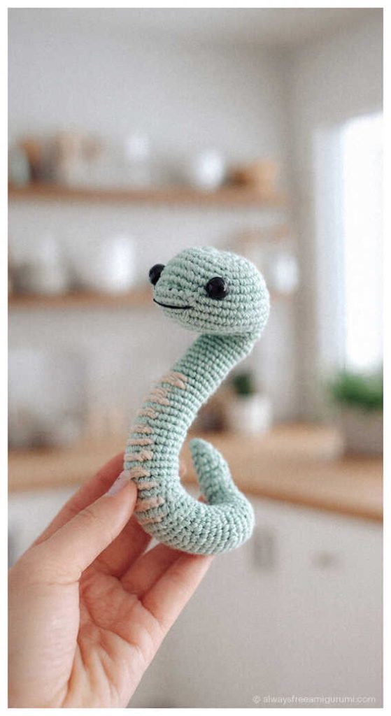 Light mint green snake amigurumi with long curved neck, minimalist crochet snake plush idea for modern home